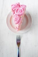 fetta sottile festiva di torta di compleanno rosa con fiori a velo e forchetta piatta foto