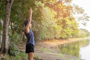 donna jogging che si estende vicino al lago al mattino. foto