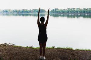 silhouette donna jogger che si estende vicino al lago. foto