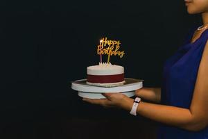 donna che tiene la torta di compleanno con candela e piatto di compleanno. foto