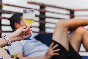 donna che tiene un bicchiere di birra sulla spiaggia. foto