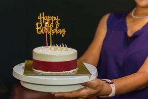 donna che tiene la torta di compleanno con candela e piatto di compleanno. foto