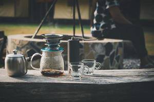 la macchina per il caffè è posizionata sopra una sedia di legno nell'area del campeggio. foto