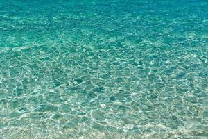 trasparente del fondo di struttura della superficie dell'acqua di mare. foto