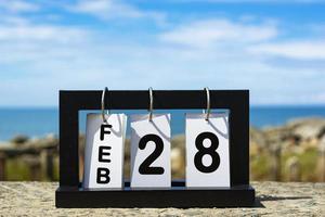 28 febbraio testo della data del calendario su telaio in legno con sfondo sfocato dell'oceano foto