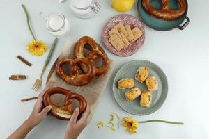 vista dall'alto piatto per uno spuntino con mano, pretzel, biscotti e rotolo di pasta con formaggio fuso. adatto per feed di social media o pubblicità foto