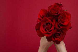 inviare fiori concetto online. consegna di fiori per San Valentino, festa della mamma. bouquet di rose rosse isolato su sfondo rosso. cartolina di design bella natura rosa. vista dall'alto. copia spazio. messa a fuoco selettiva foto