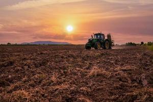 macchina che lavora in terreni agricoli al tramonto, piantando canna da zucchero macchina funzionante foto