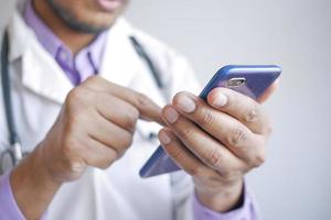 medico in camice bianco utilizzando uno smartphone. foto