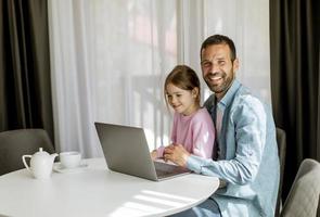 padre e figlia che usano insieme il computer portatile foto