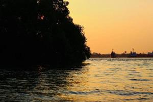 bellissimo tramonto sul fiume con nave da carico e barca in tailandia foto