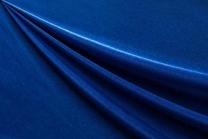 fondo di lusso in tessuto blu scuro. modello di piega ondulata liscia. curva elegante. struttura del materiale in velluto di seta. foto