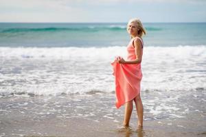 donna anziana che si gode il suo tempo libero guardando il mare dalla riva della spiaggia. foto