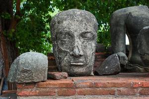 la testa di un'immagine di buddha di pietra su un vecchio recinto al tempio di ratchaburana. foto