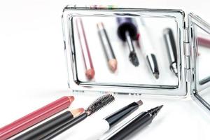 matite cosmetiche, eyeliner e carcasse sullo sfondo di uno specchio foto