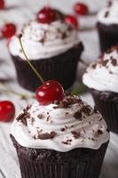 cupcakes al cioccolato con crema e ciliegia vicino, verticale foto