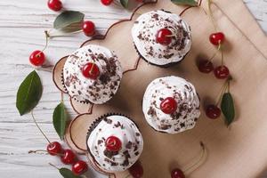 cupcakes al cioccolato con top orizzontale primo piano crema e ciliegia foto