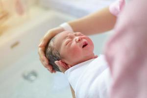 neonato asiatico che fa il bagno da sua madre, bambino foto