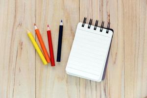 piccolo taccuino o blocco note per scrivere informazioni con matita colorata su un tavolo di legno. vista dall'alto foto