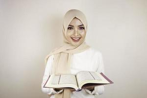 giovane donna musulmana asiatica che sorride e che tiene il quran foto