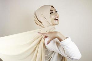 donna musulmana che indossa abiti tradizionali e hijab isolati su sfondo bianco. l'hijab è fatto volare in modo creativo. idul fitri e concetto di moda hijab. foto