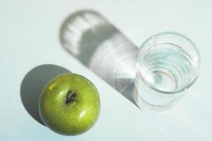 stile di vita sano e concetto di dieta con una mela verde e un bicchiere d'acqua. foto