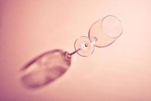 bicchiere di vino vuoto con ombra scura creativa su sfondo rosa. foto