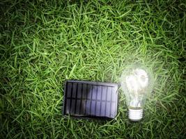 cella solare e lampadina su erba verde, risparmio energetico, utilizzo di energia verde rinnovabile per salvare il mondo, amare e proteggere il nostro pianeta, concetto rispettoso dell'ambiente foto