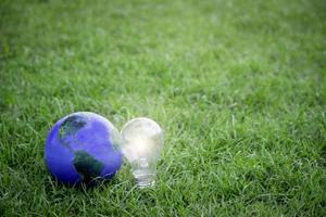 terra con lampadina su erba verde, risparmio energetico, salva il mondo, ama e proteggi il nostro pianeta, concetto rispettoso dell'ambiente foto