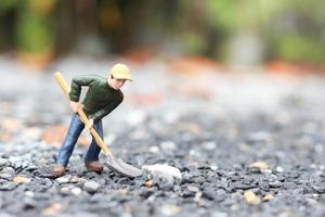 bambola lavoratore in miniatura che tiene pala per il lavoro, minatore uomo al lavoro piccola figura giocattolo modello scavando terreno o giardinaggio foto