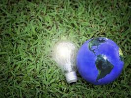 terra con lampadina su erba verde, risparmio energetico, salva il mondo, ama e proteggi il nostro pianeta, concetto rispettoso dell'ambiente foto