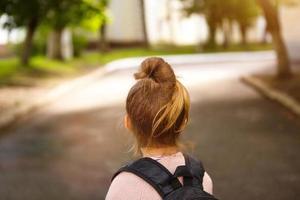 una bambina di razza caucasica in uniforme scolastica con uno zaino guarda la strada nel cortile della scuola. concetto di ritorno a scuola. scuola elementare, sviluppando attività per bambini in età prescolare. spazio per il testo foto