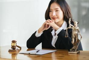 avvocato asiatico femminile serio con sorridente seduto sul posto di lavoro e guardando la fotocamera foto