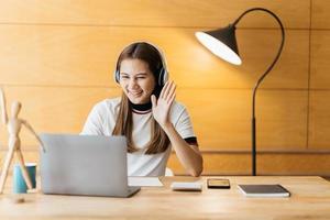 sorridente giovane donna asiatica che utilizza l'auricolare guardando lo schermo del laptop ascolta e impara corsi online. felice donna d'affari cinese con le cuffie videochiamata per il servizio clienti foto