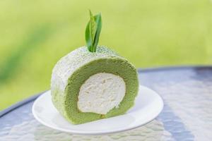 torta di tè verde e rotolo con foglia di tè sul piatto bianco. foto