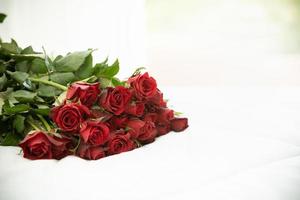 concetto di amore e san valentino. primo piano del bouquet di rose rosse sul letto bianco con spazio per la copia. foto