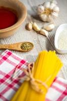 spaghetti e altri ingredienti, parmigiano, origano sul tavolo della cucina
