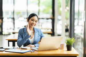 femmina asiatica che parla del rapporto di vendita in videoconferenza. squadra asiatica che utilizza laptop e tablet incontro online in videochiamata. lavorare da casa in remoto. foto