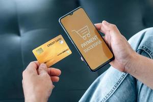 pagamento online, internet banking e concetto di shopping online. l'uomo d'affari tiene la carta di credito e utilizza lo smartphone con successo sul tavolo. foto