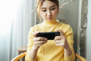 donna asiatica eccitata mentre gioca a giochi mobili, legge buone notizie mentre naviga nel mondo di Internet. foto