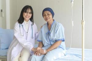 medico che tiene la mano del malato di cancro anziano in ospedale, assistenza sanitaria e concetto medico foto