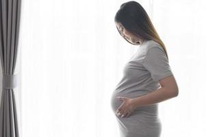 giovane bella donna incinta a casa, maternità e concetto di cura della gravidanza foto