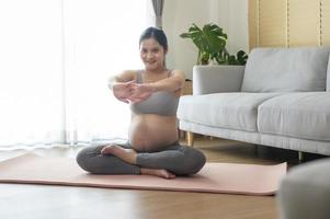 giovane donna incinta che fa yoga a casa, concetto di assistenza sanitaria e gravidanza foto