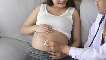 un medico che tiene uno stetoscopio sta esaminando una donna incinta nel concetto di ospedale, assistenza sanitaria e gravidanza foto