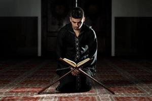 giovane musulmano che legge il Corano foto