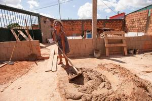 planaltina goias, brasile, 16 aprile 2022 una giovane ragazza che dimostra come mescolare il cemento con una zappa su una casa in costruzione per la sua famiglia foto