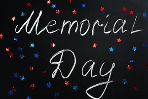 iscrizione scritta a mano memorial day su una lavagna nera e stelle blu e rosse americane sullo sfondo. concetto di vacanza. foto