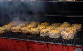 polpette di hamburger fatte a mano durante il festival del cibo di strada, affumicate durante la cottura. foto