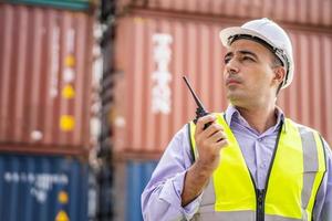 giovane ingegnere o manager maschio uso della comunicazione radio per controllare il carico del container nei concetti di trasporto industriale e logistica. foto