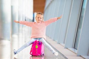 adorabile bambina divertirsi in aeroporto seduto sulla valigia
